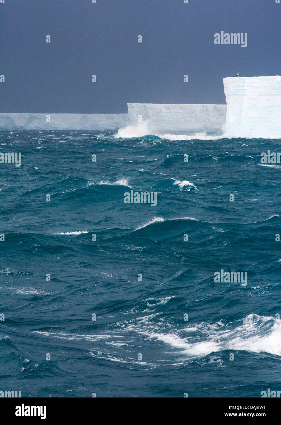 Rough seas batter blue tabular icebergs in the Southern Ocean Antarctica Stock Photo