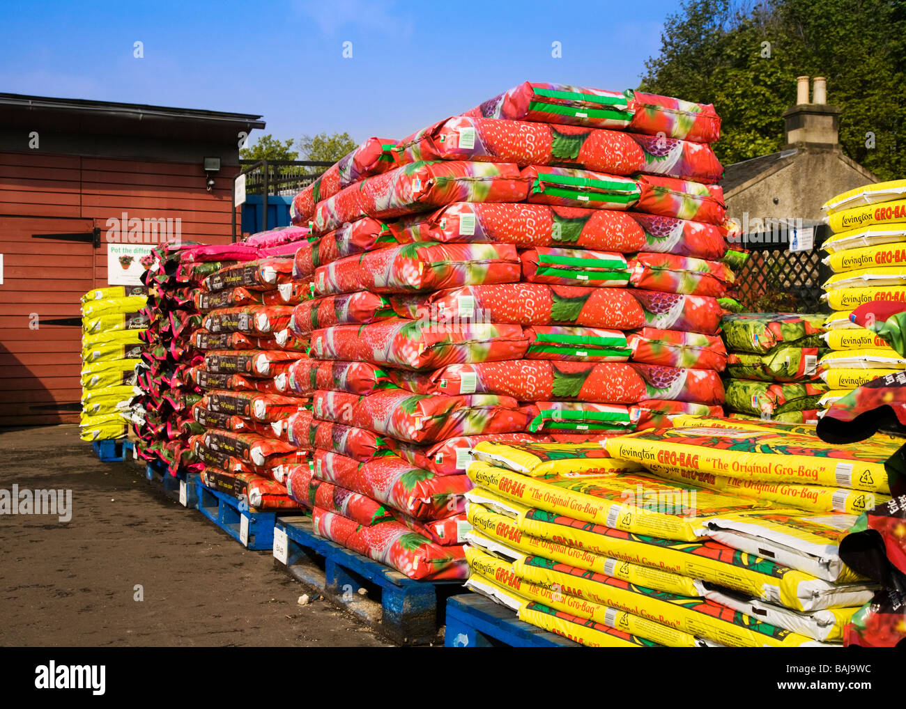 Bags of compost stacked on pallets at a garden centre. Stock Photo