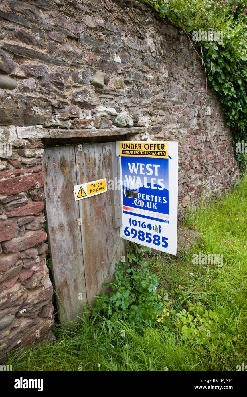 Estate agent s sign on a derelict cottage for sale Stock Photo