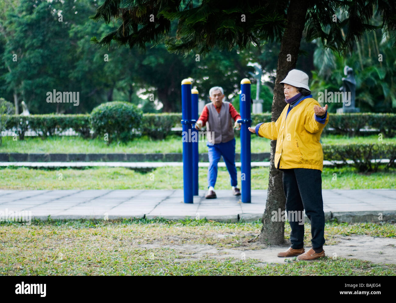 two elderly people man and female exercising in a park in the early morning in Taipei dressed in bright cloths Stock Photo