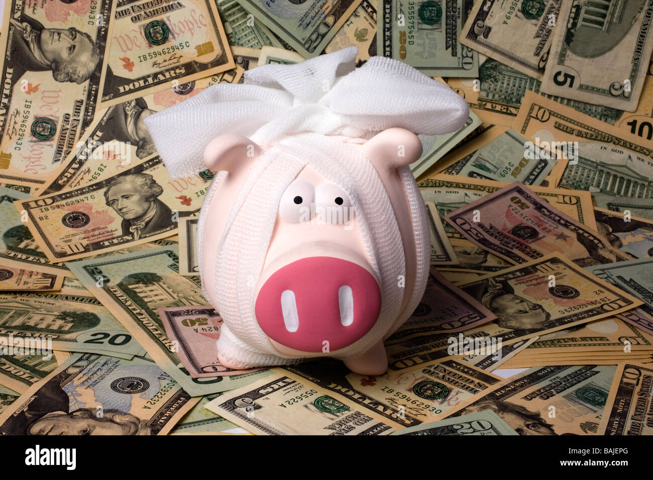 piggy bank in bandages sitting on a pile of American dollars Stock Photo
