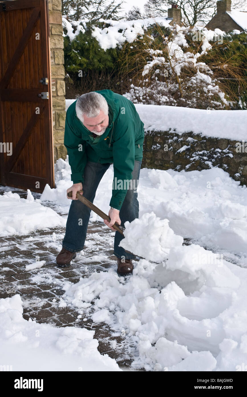 A man clearing snow off a driveway Stock Photo