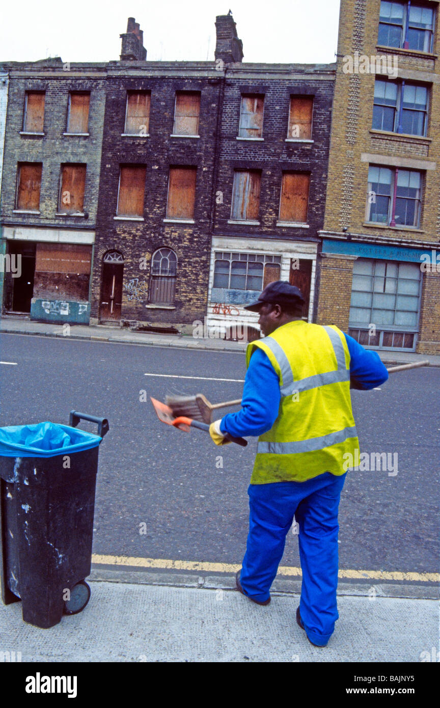 Street cleaner in boarded up street of derelict Victorian houses London SE1 England Stock Photo