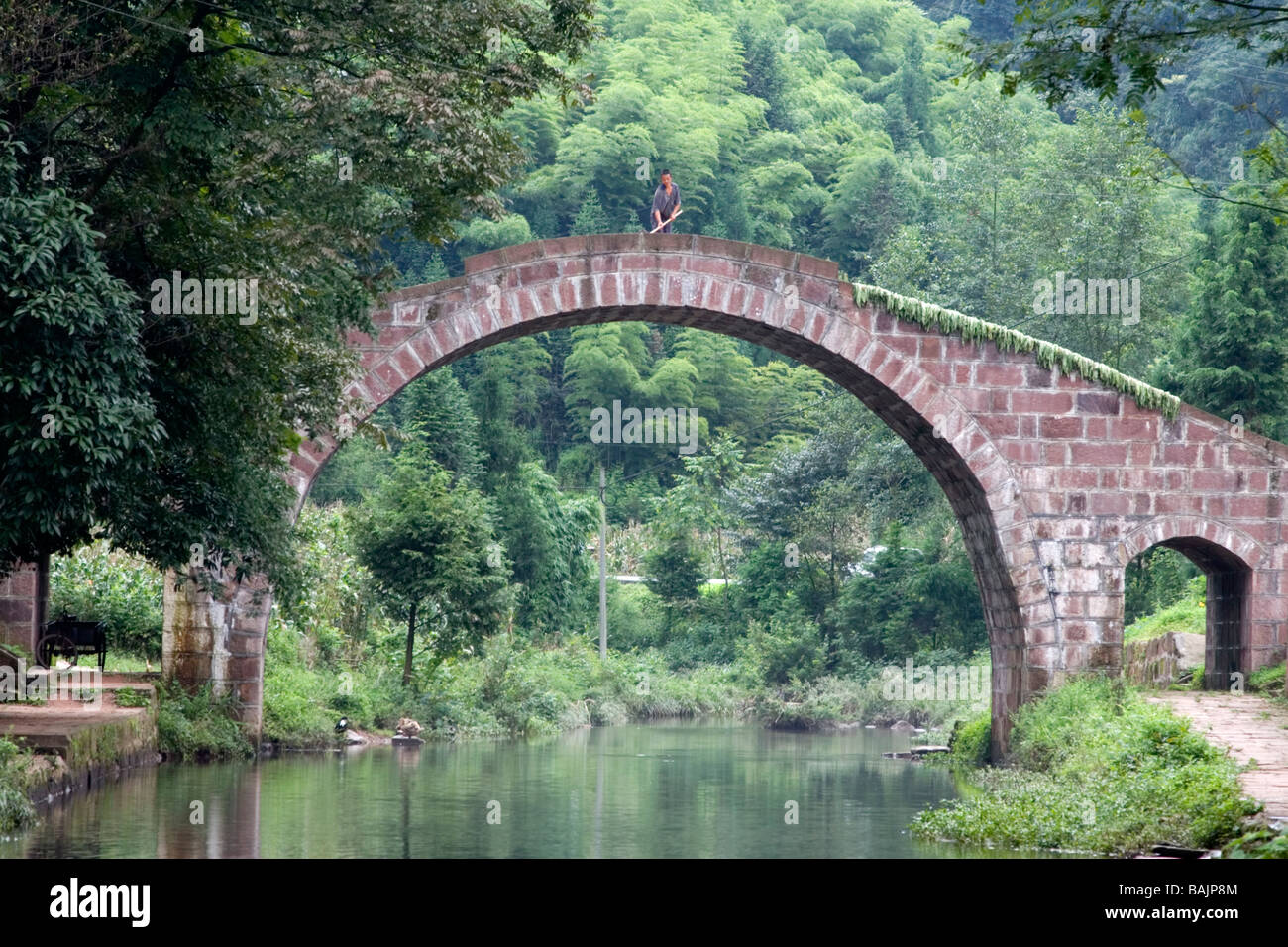 An old arched stone bridge over the stream in the old village of ...
