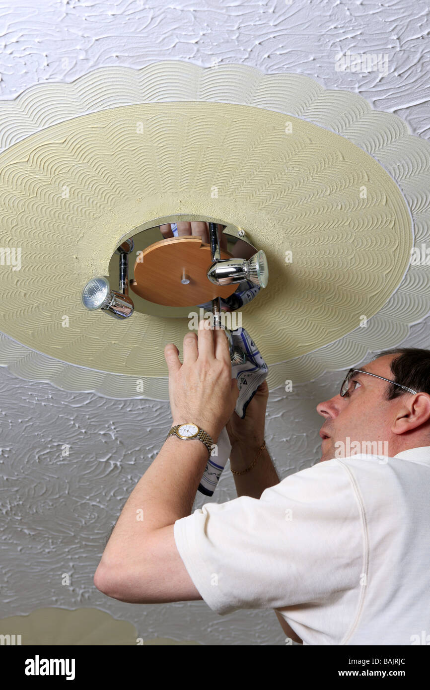 A Man Changes A Halogen Lightbulb In A Ceiling Light Fitting Stock