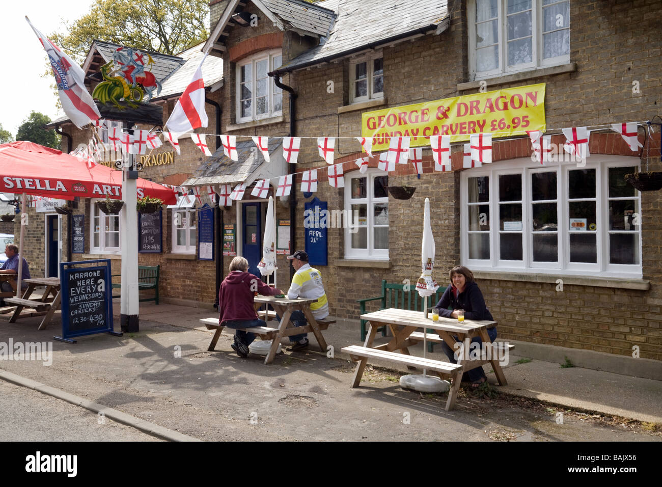 People drinking beer outside the George and Dragon pub, on St Georges day, Snailwell, Cambridgeshire UK Stock Photo