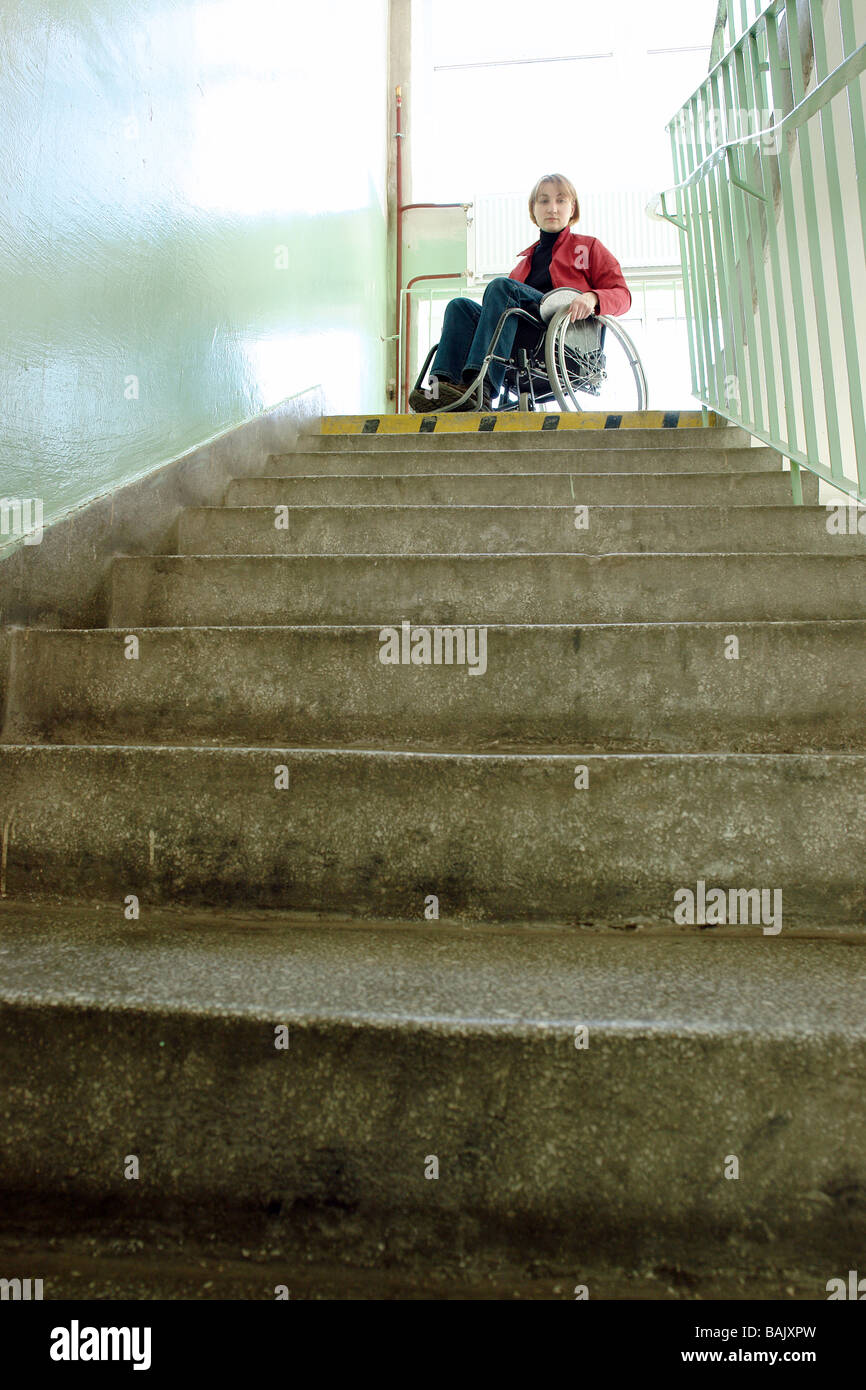 Handicapped woman on wheelchair looking down the stairs in building