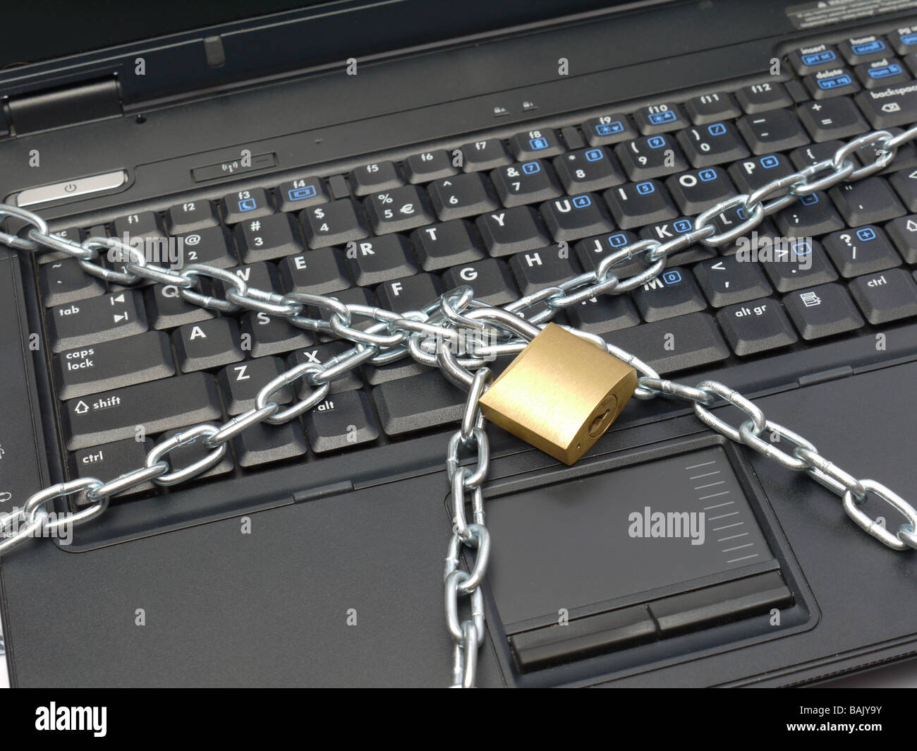 Closeup of laptop keyboard wrapped around with metal chain and locked