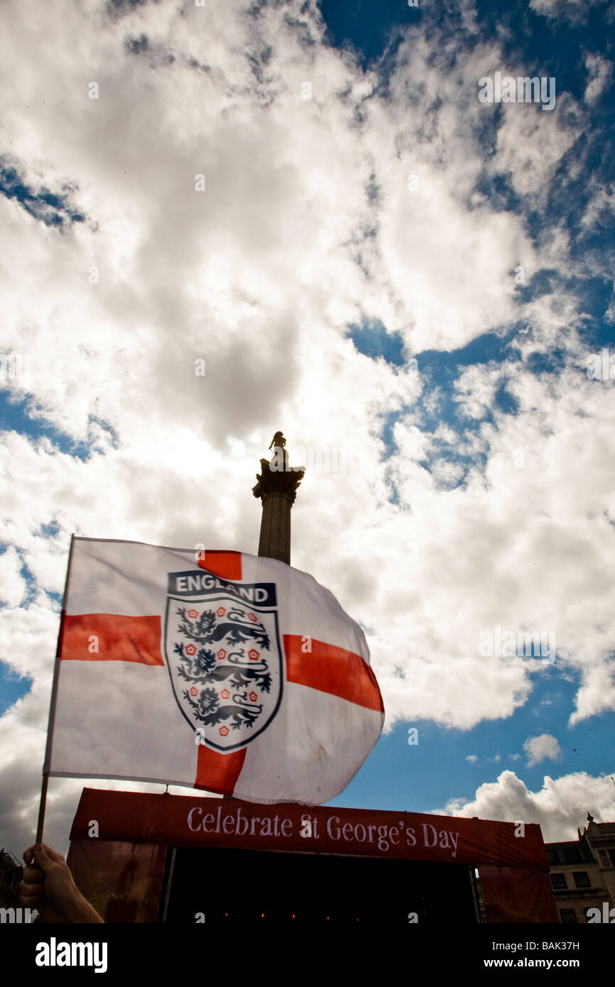 Backlit England flag being waved in Trafalgar Square during St George's Day celebrations, Nelsons Column in background. Stock Photo