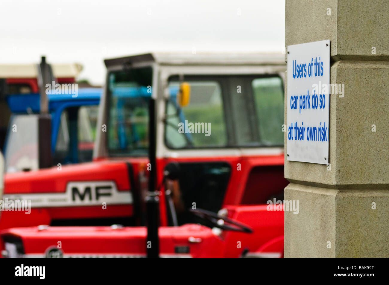 Sign in a car park 'Users of this car park do so at their own risk' with farm tractors parked in the background. Stock Photo