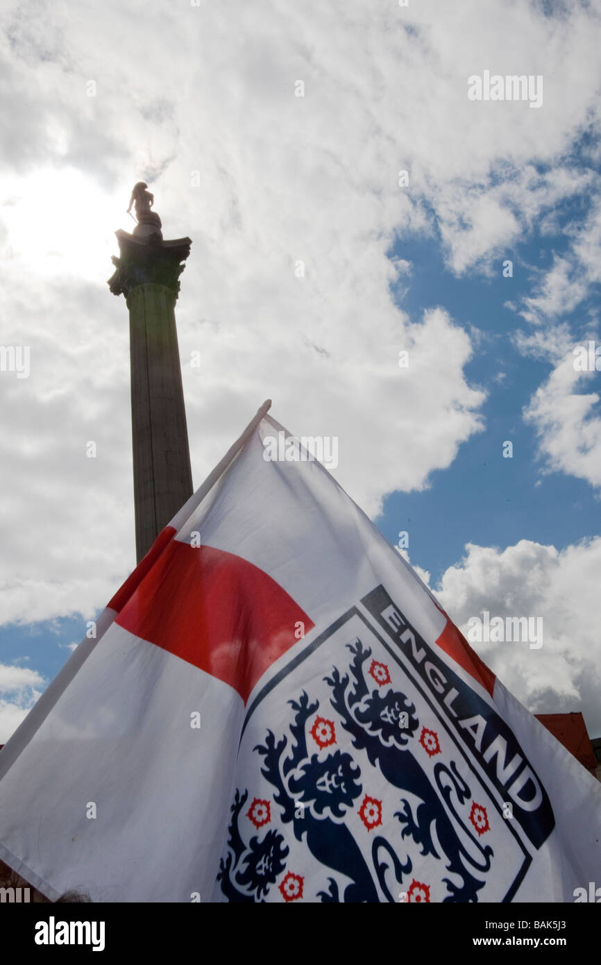 England flag being waved in Trafalgar Square during St George's Day celebrations, Nelsons Column in background. Stock Photo