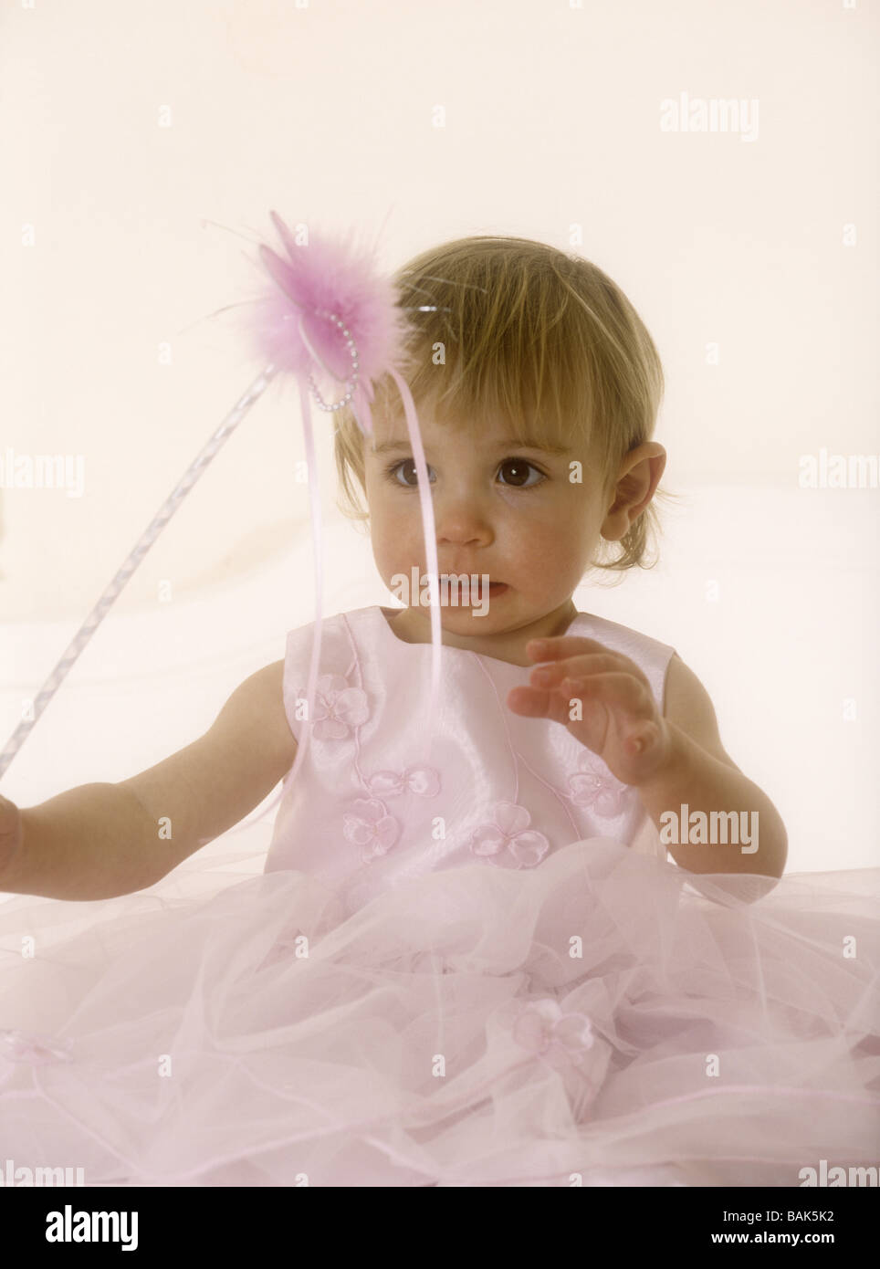 Toddler wearing a pink party dress holding a wand Stock Photo