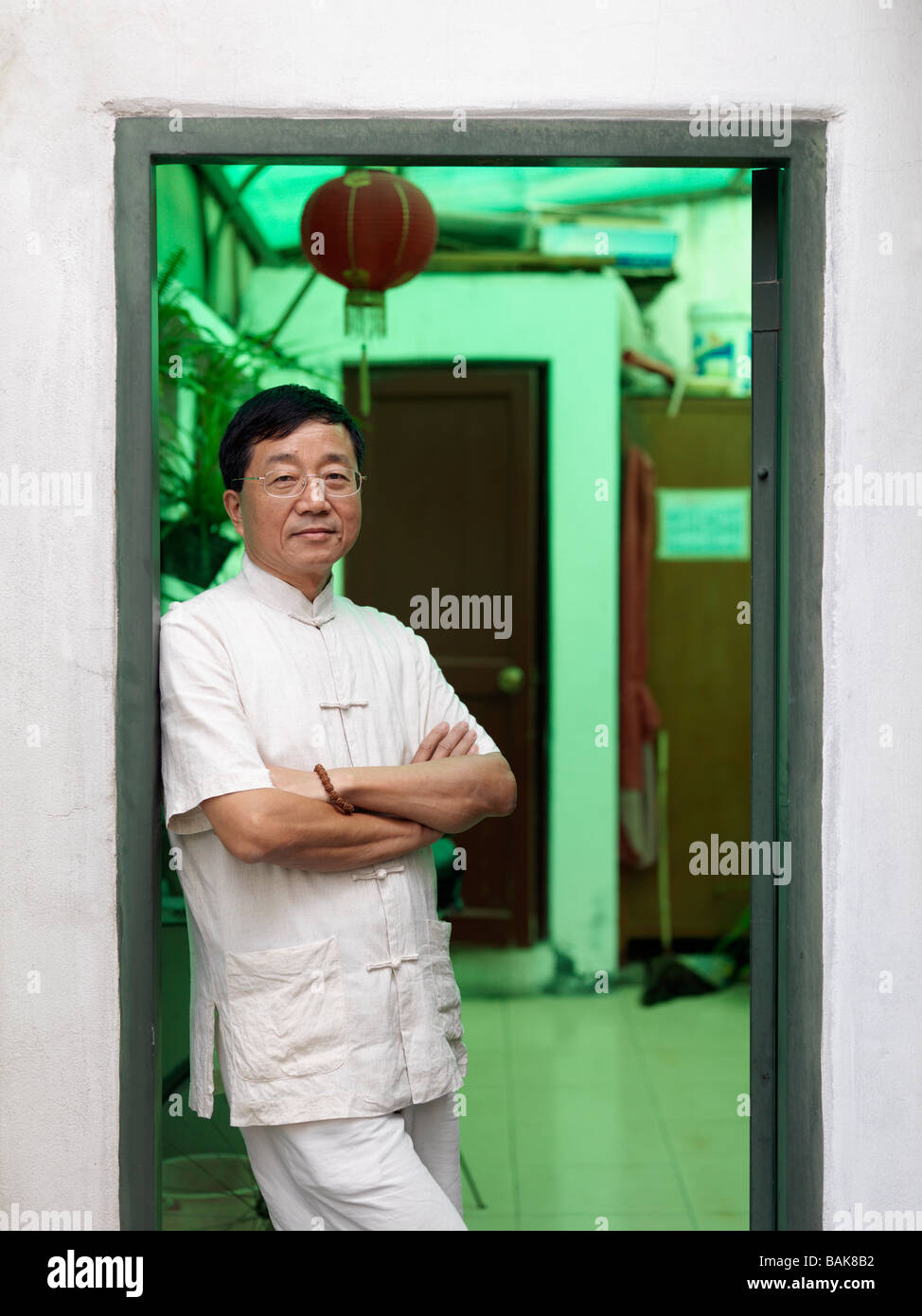 A portrait of a Chinese man leaning in a doorway. Stock Photo