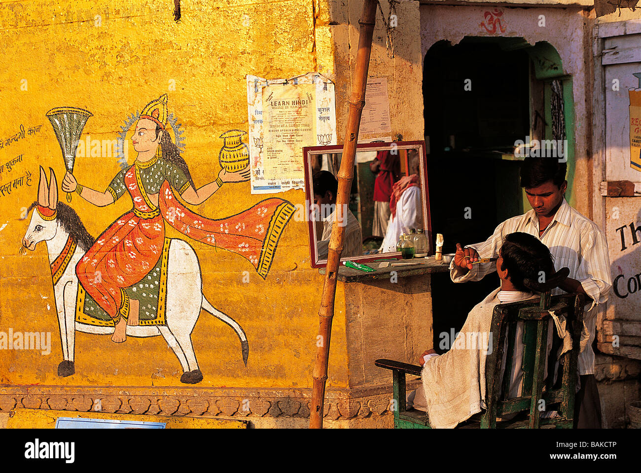India, Uttar Pradesh State, Varanasi, barber and wall painting Stock