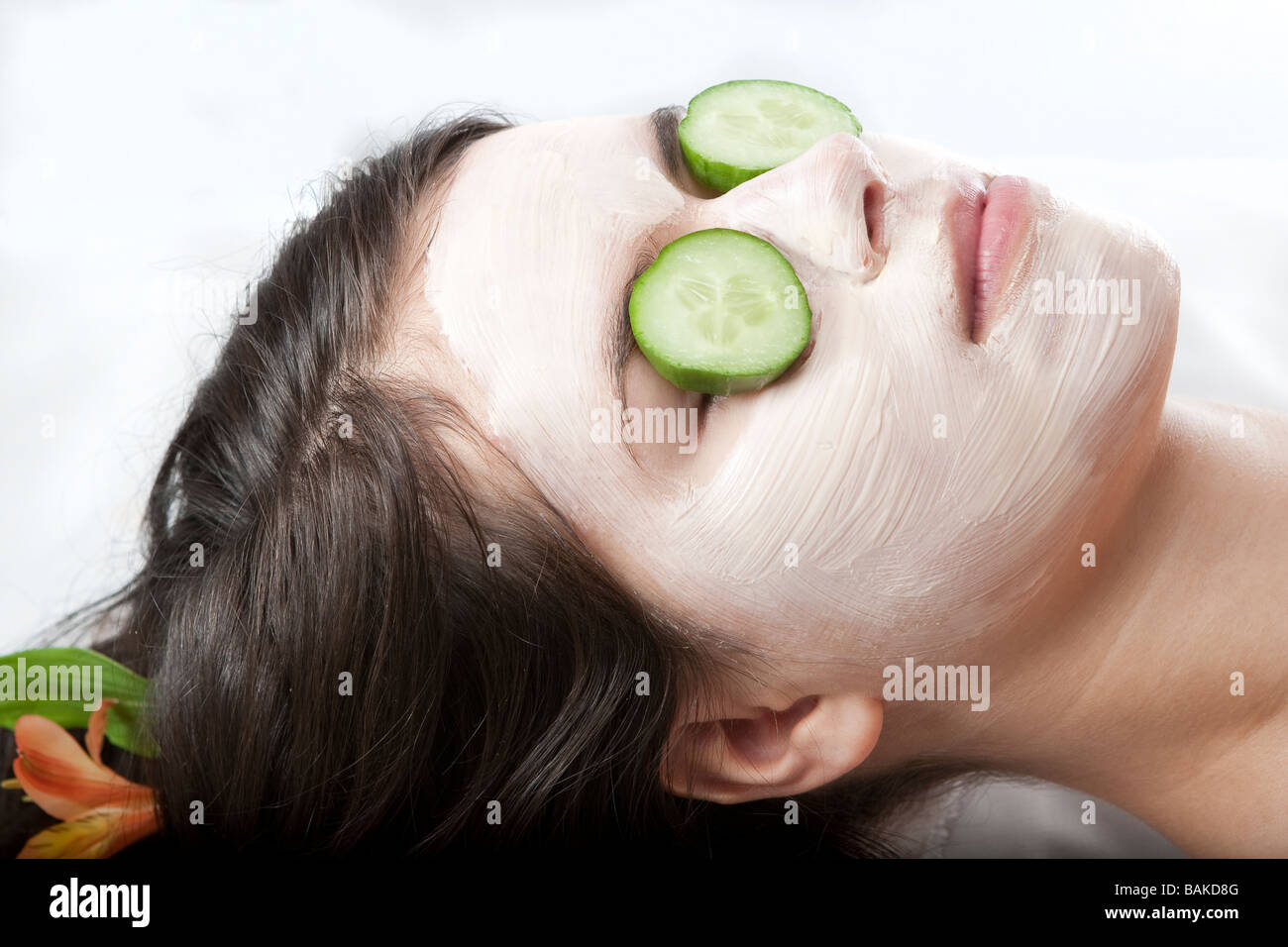Young woman getting a facial treatment with cucumbers on her eyes at a
