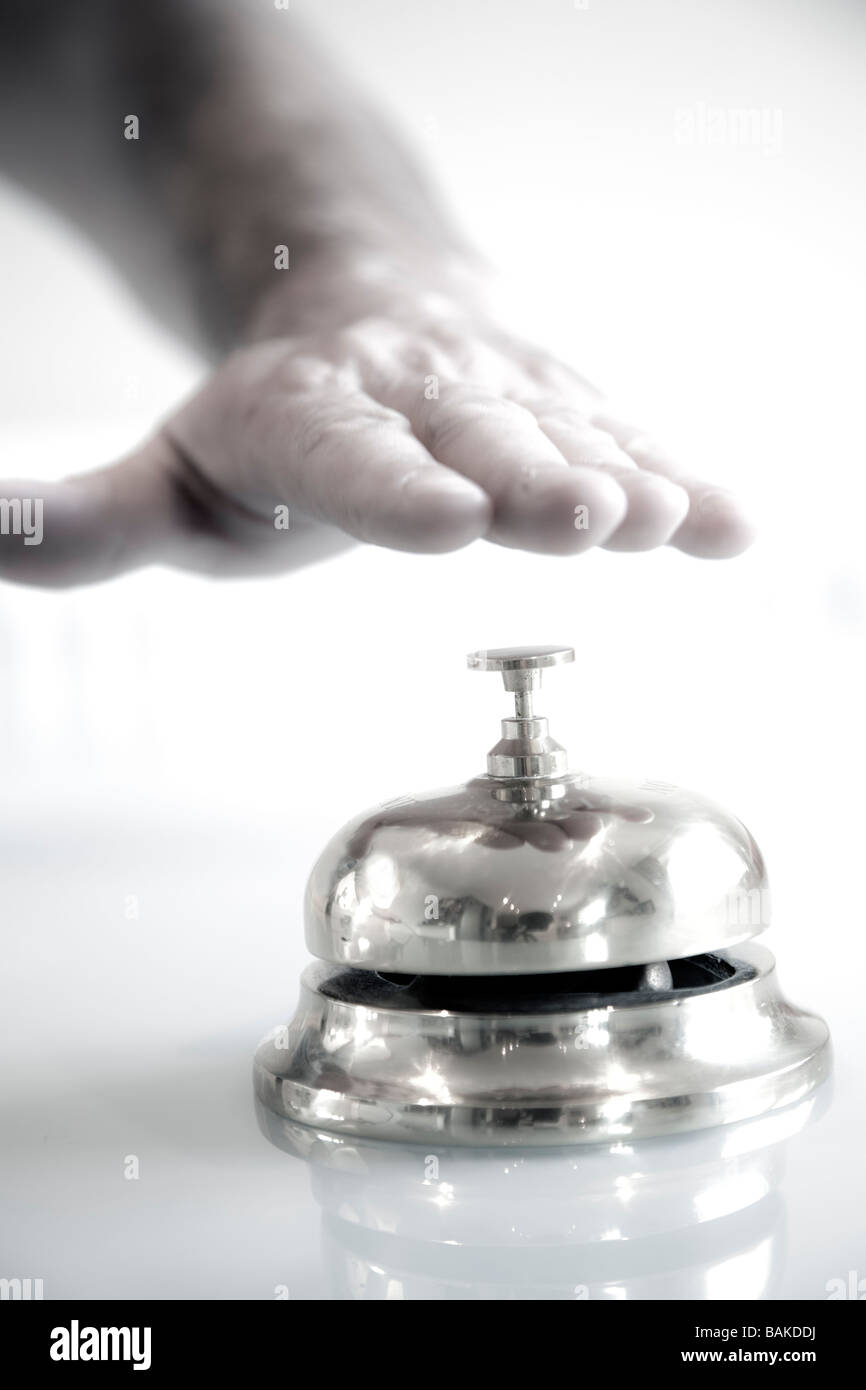 A male person hand about to press a concierge bell for attention on a clear counter top Stock Photo