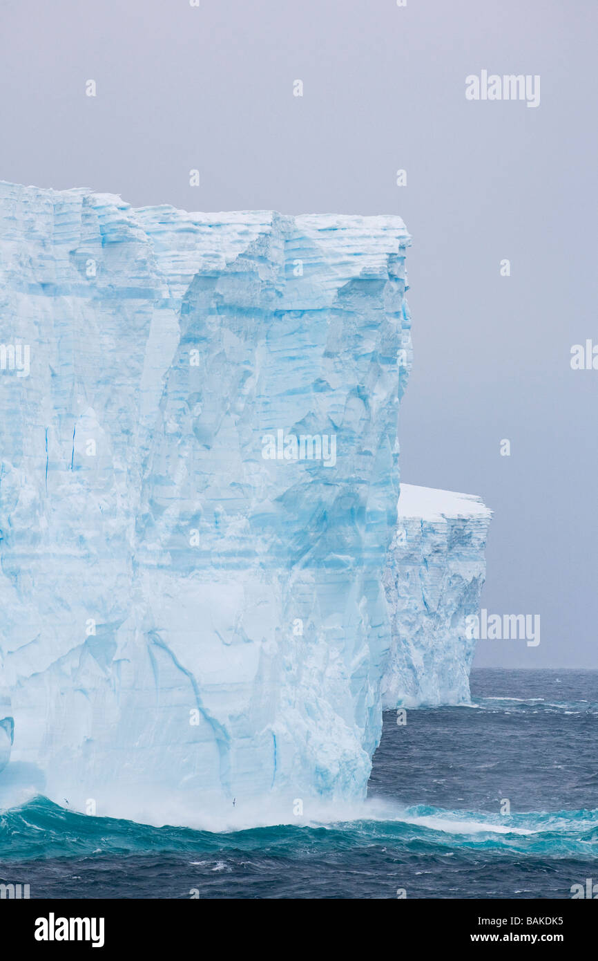 Rough seas breaking on blue tabular icebergs Southern Ocean Antarctica Stock Photo