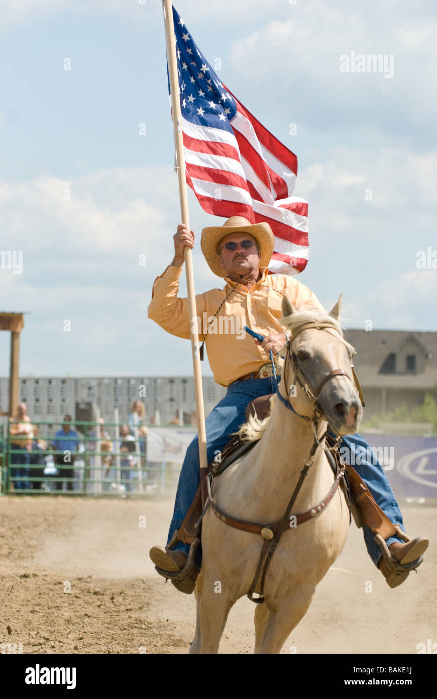 Man on horse carrying American flag at rodeo event Stock Photo Alamy