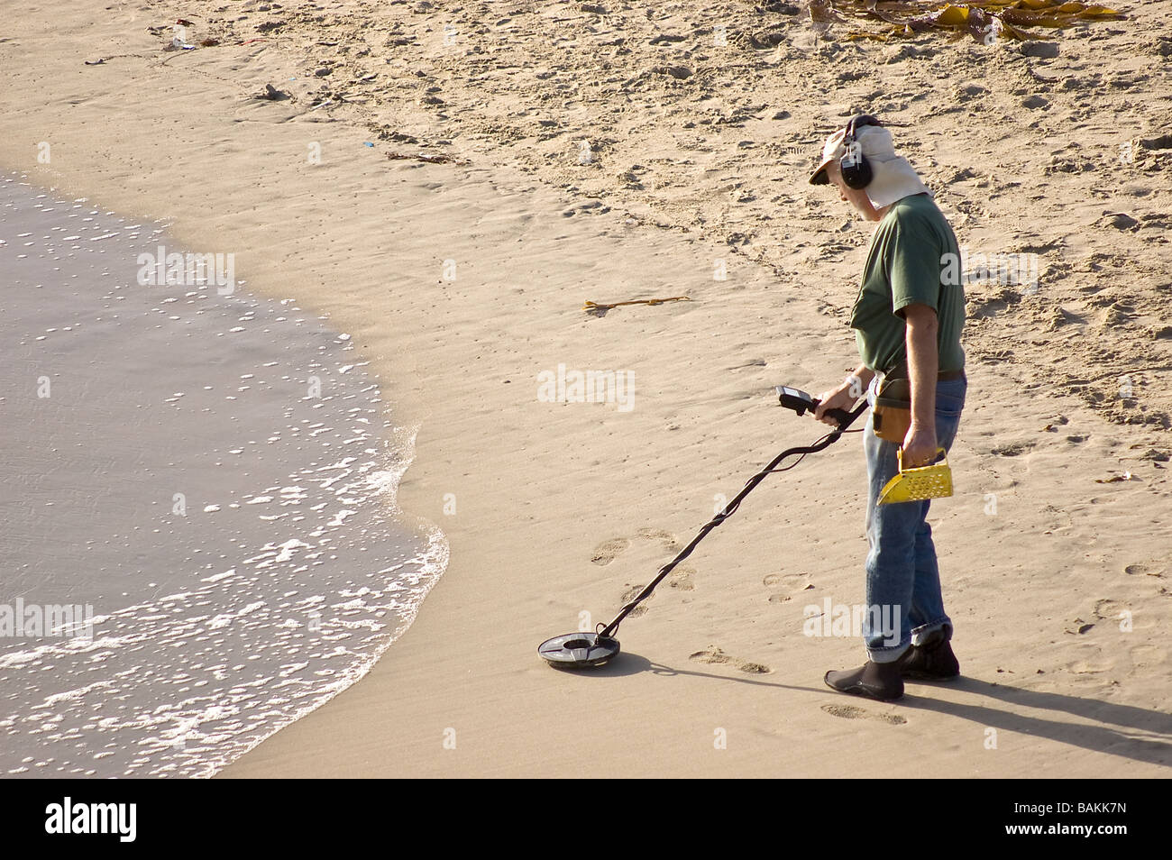 A man with a metal detector looking for valuable items on the beach;  Huntington Beach, California, USA Stock Photo - Alamy