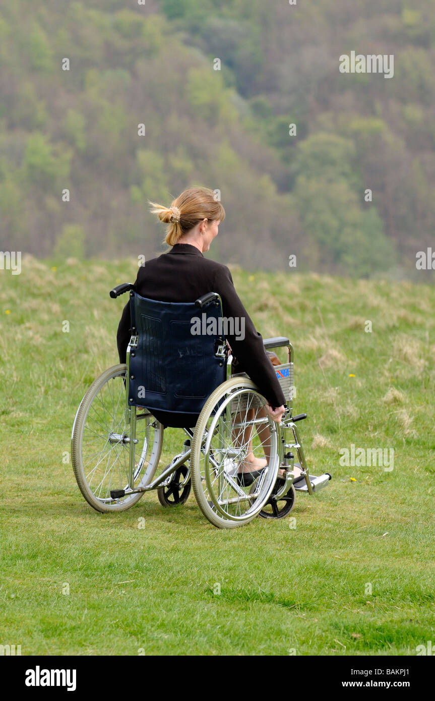 woman sitting in a self propel dma wheelchair overlooking english countryside Stock Photo