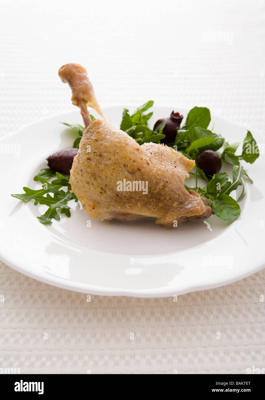 Duck Confit on a white plate with salad garnish Stock Photo
