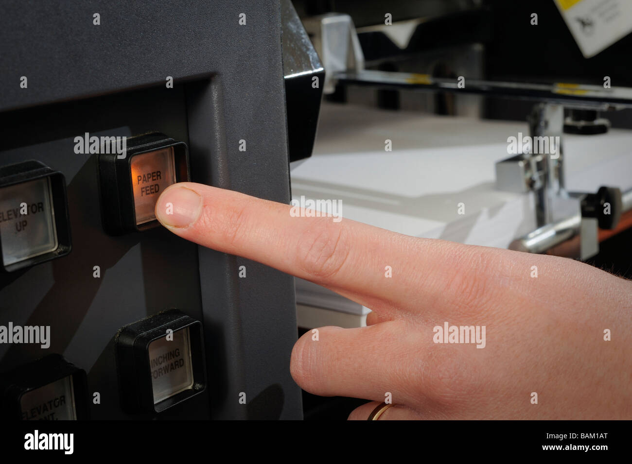 Printing press made by Hewlett Packard. An operator pressing paper feed button as the paper is loaded. Stock Photo