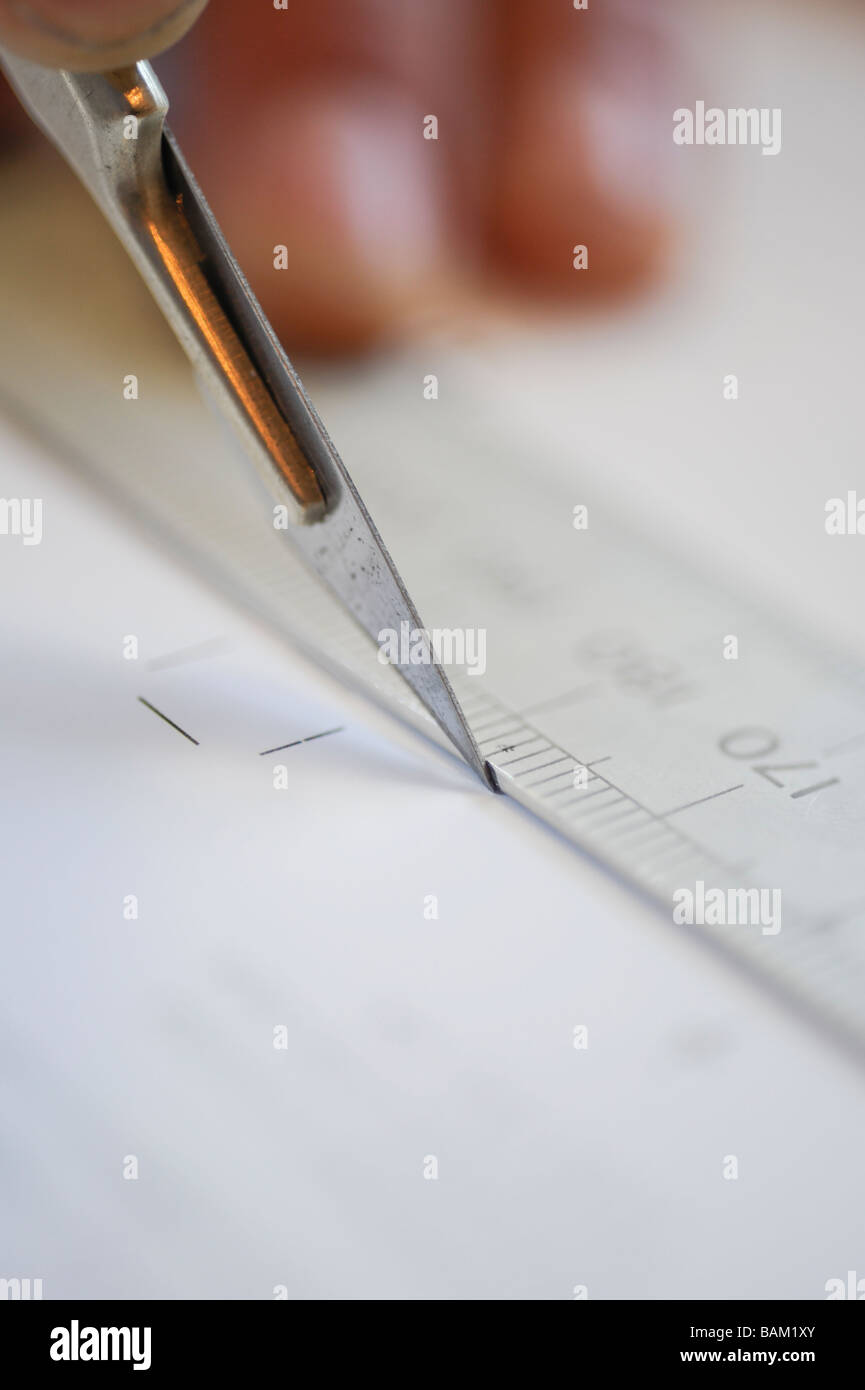 A scalpel and ruler being used to cut paper in print finishing. Stock Photo