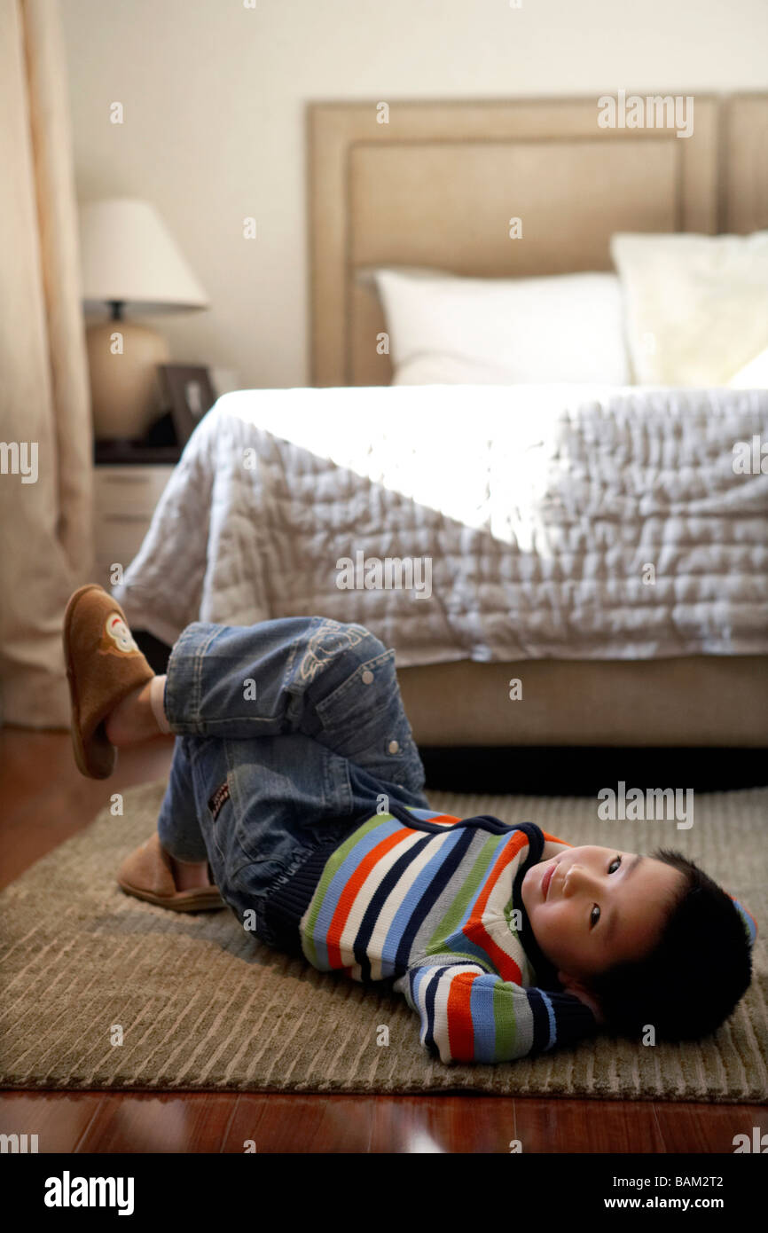 Boy Lying On Floor In Bedroom Stock Photo