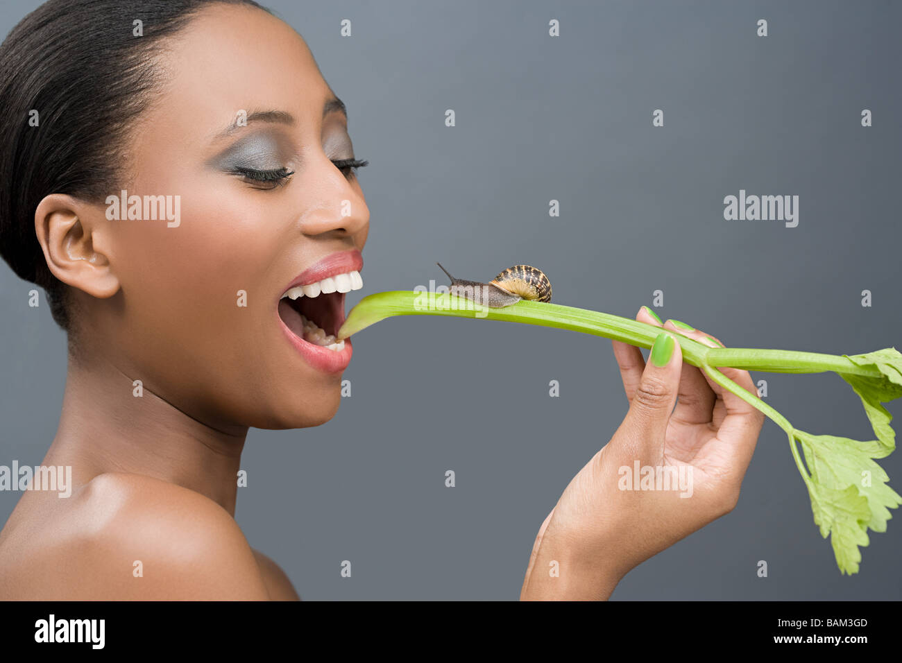 Woman eating a stick of celery with a snail on it Stock Photo