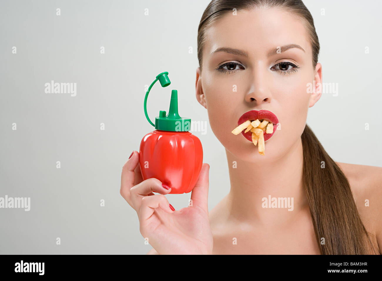 Woman holding tomato ketchup and eating fries Stock Photo Alamy