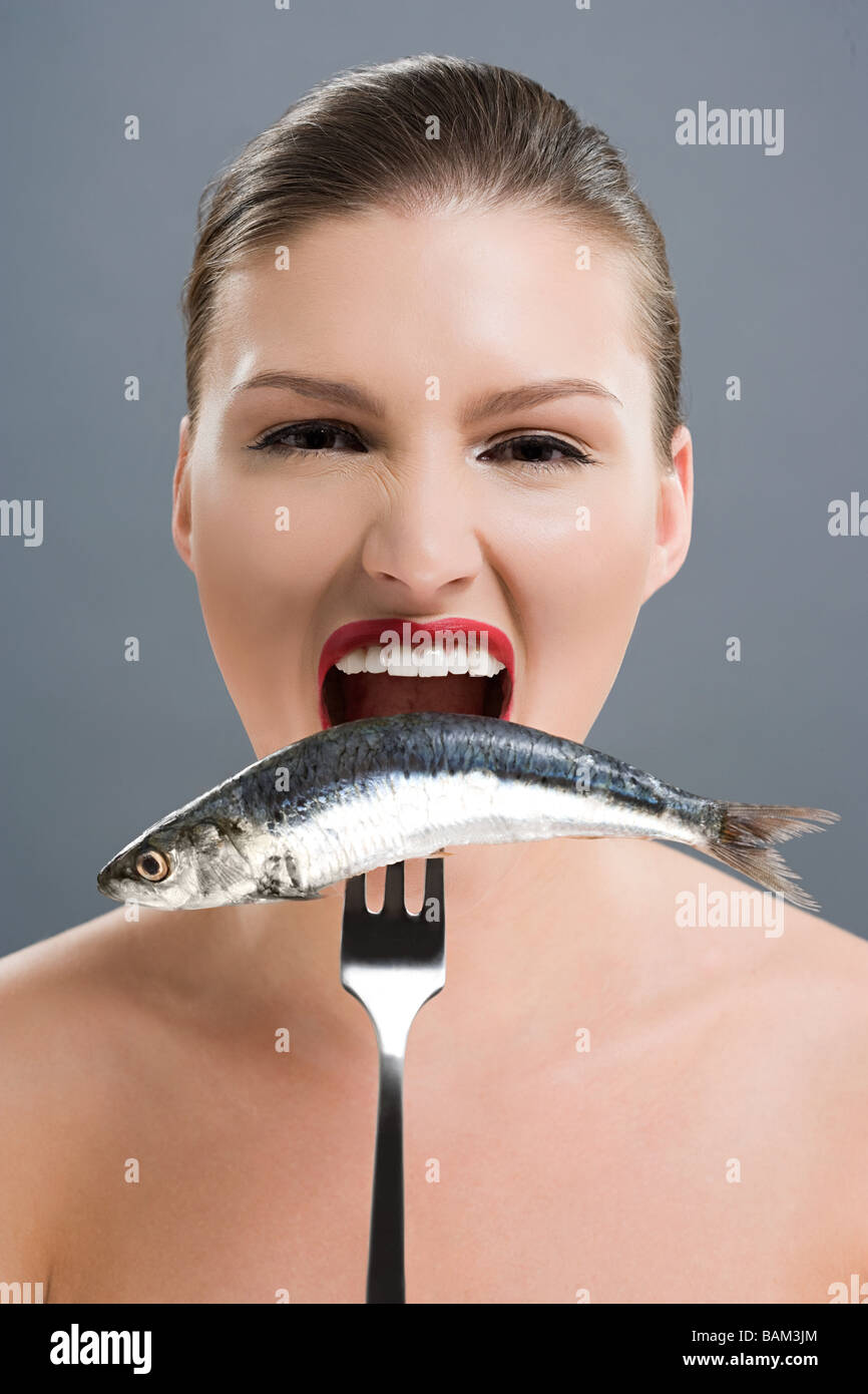 Woman biting a fish on a fork Stock Photo