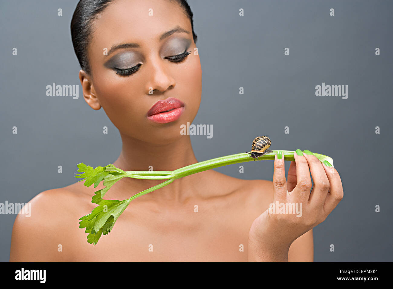 Woman looking at a snail on a stick of celery Stock Photo