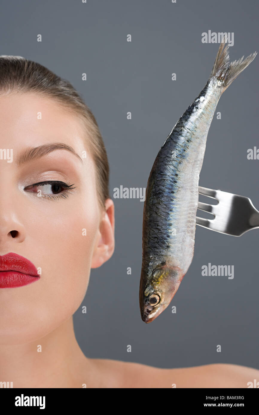 Woman looking at a fish on a fork Stock Photo