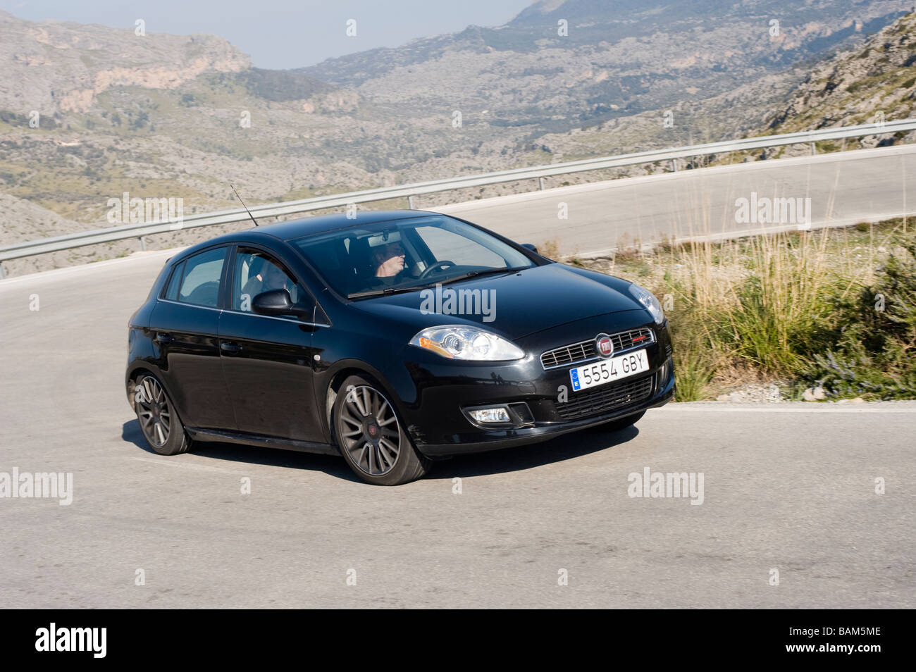 Black Fiat Bravo Multijet car being driven around a bend on a road in Spain Stock Photo