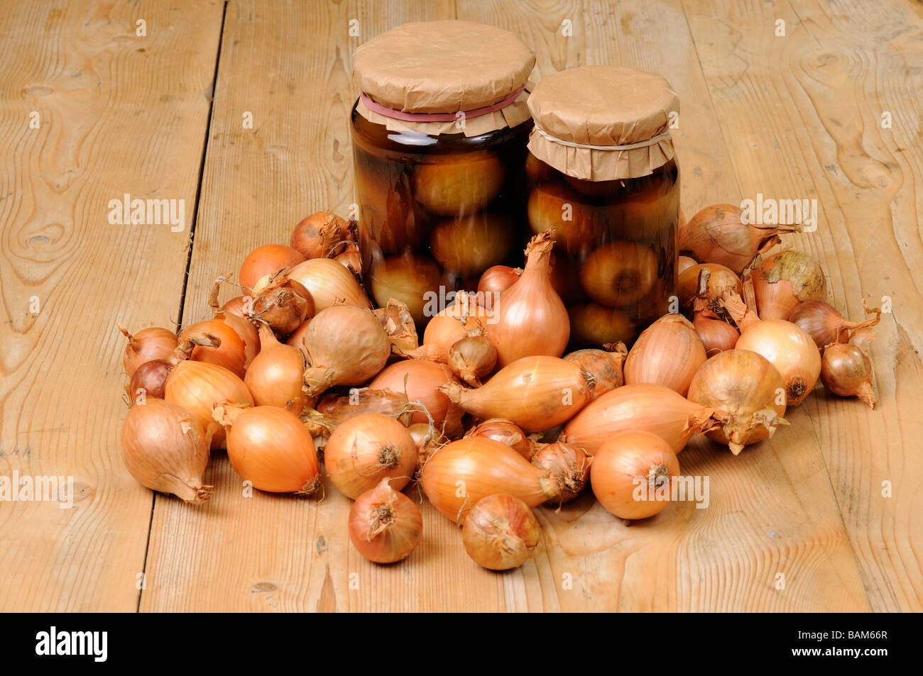 Two jars of home made pickled onions surounded by pickling onions on