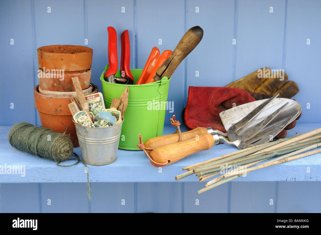 Springtime potting shed scene with shelf containing colourful garden buckets and gardening bits and pieces Stock Photo