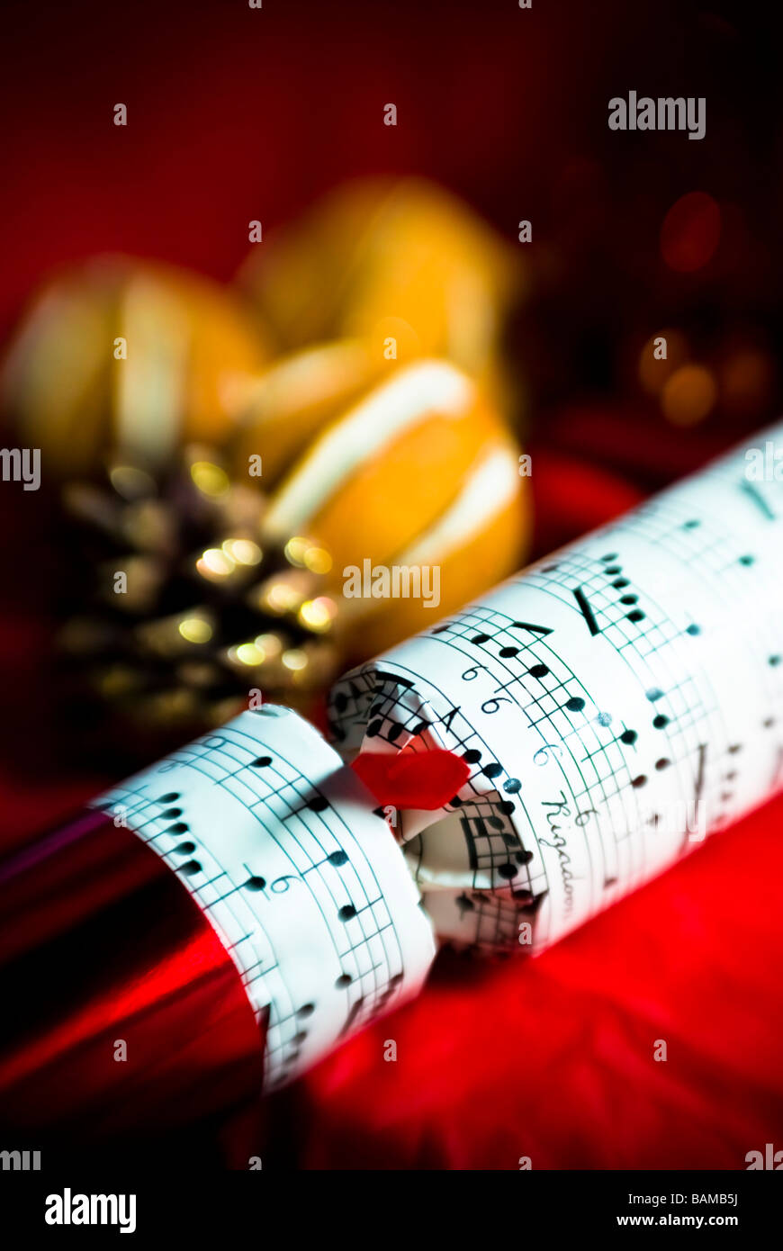 Richly-coloured Christmas scene with Christmas cracker in foreground, with atmospheric soft focus and blur Stock Photo