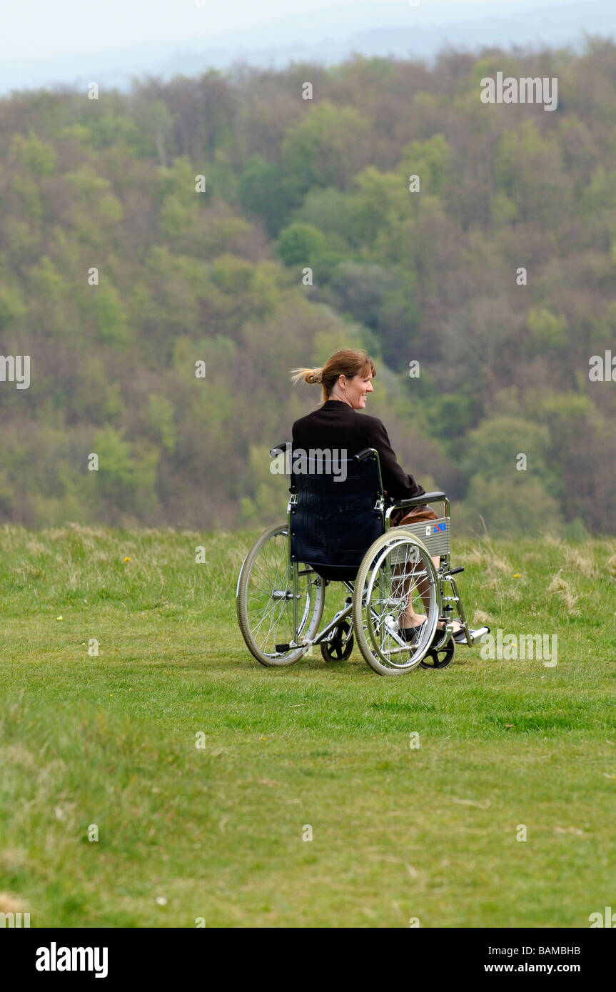 woman sitting in a self propel dma wheelchair overlooking english countryside Stock Photo