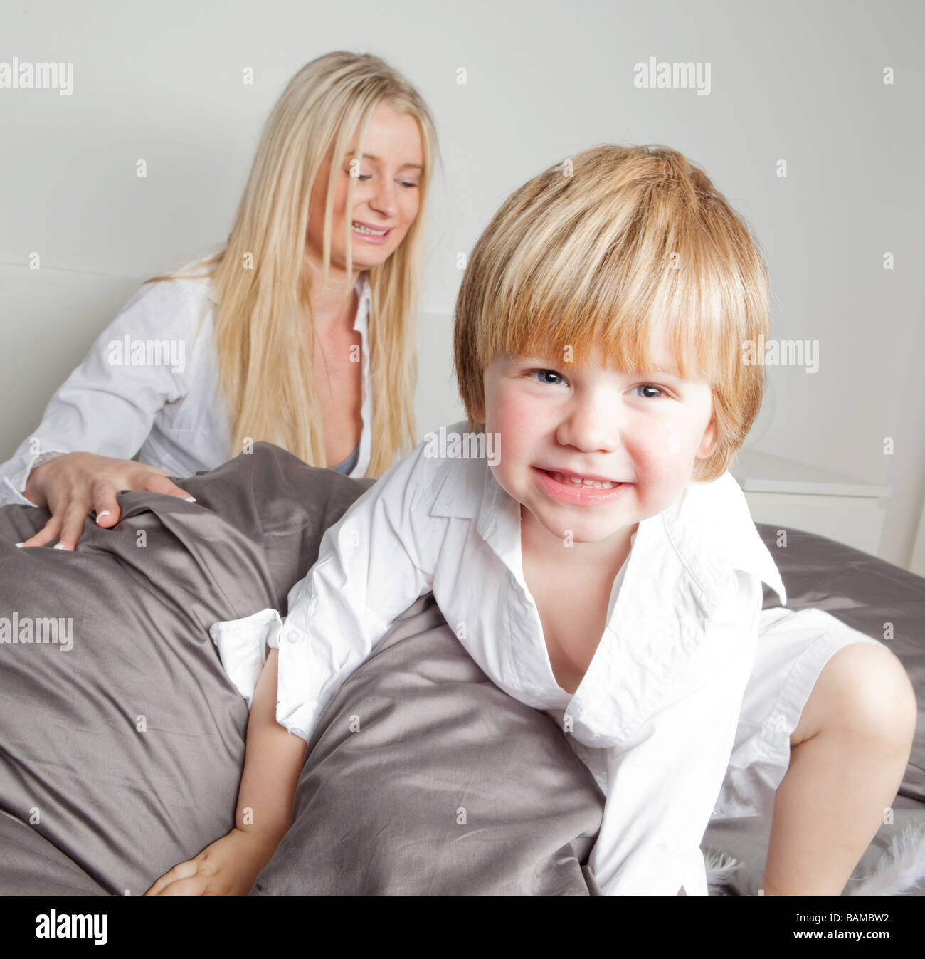 young mother with her 2 years old son on the bed playing with feathers and pillows Stock Photo