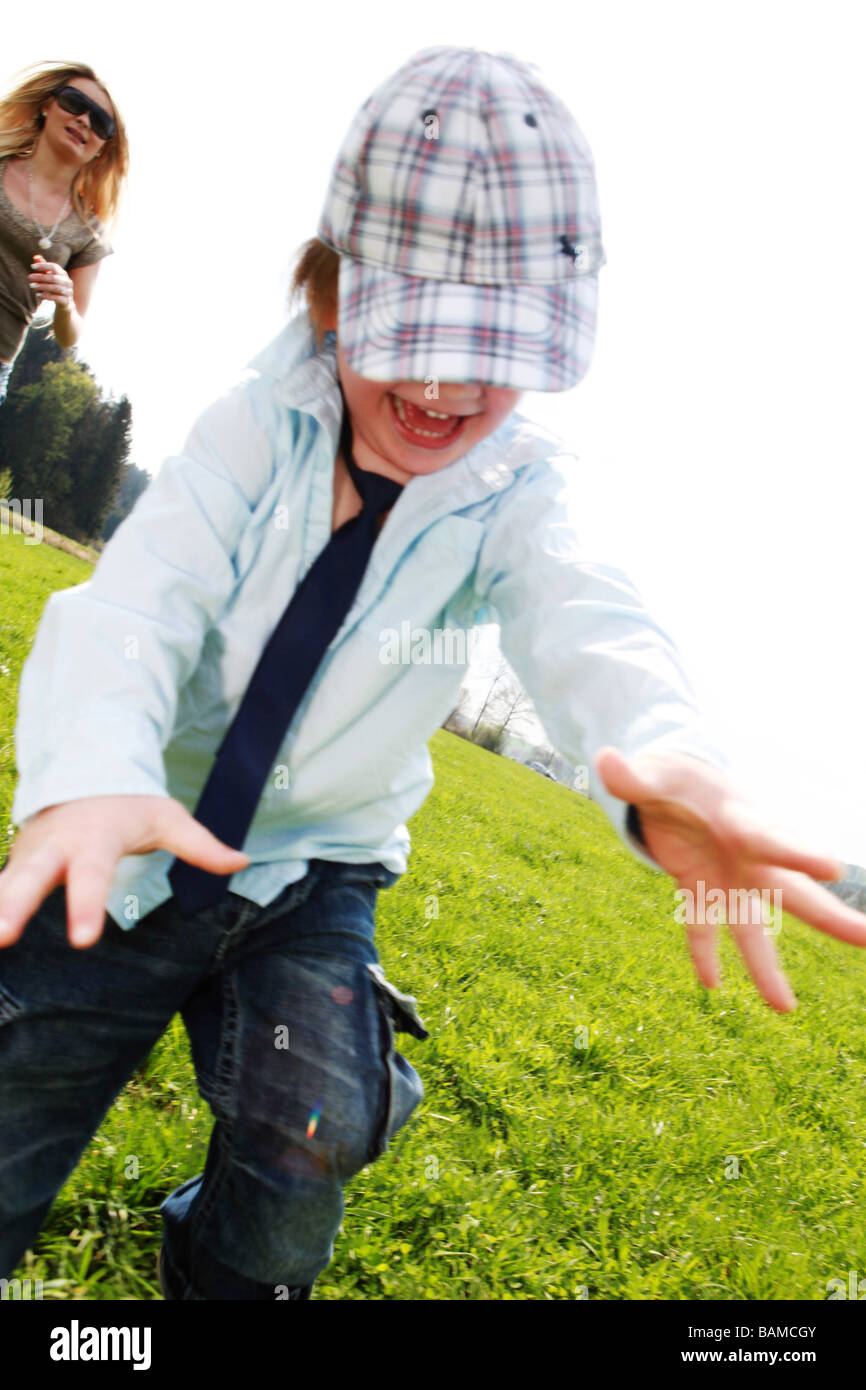 boy two years running in the meadow mother in the background Stock Photo
