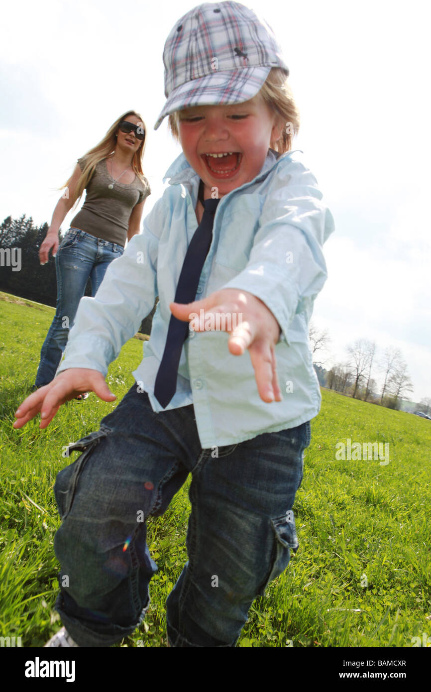 boy two years running in the meadow mother in the background Stock Photo