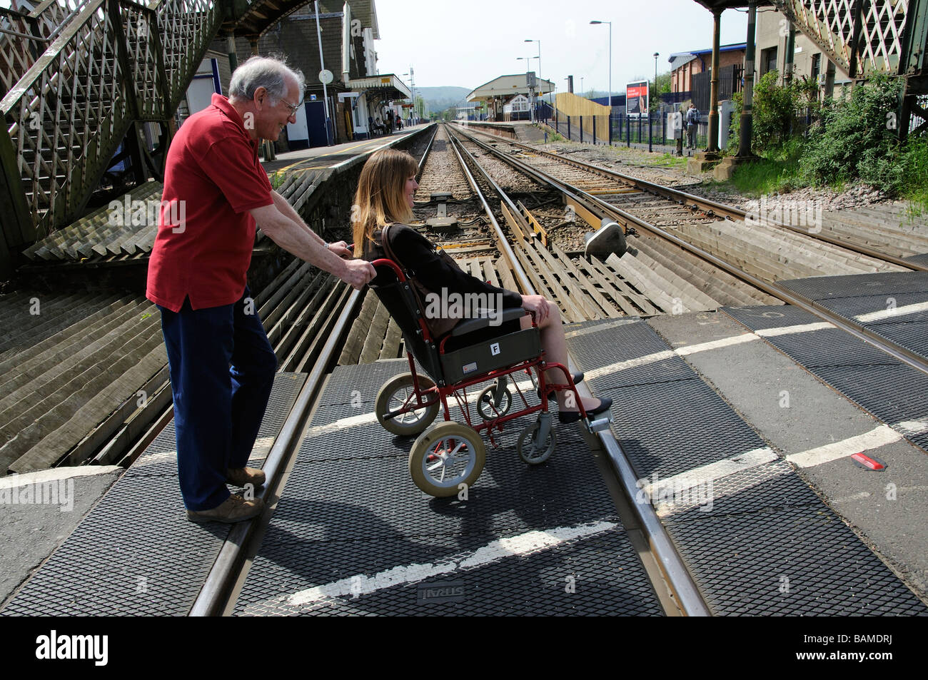Female invalid wheelchair user and male carer using a railway level
