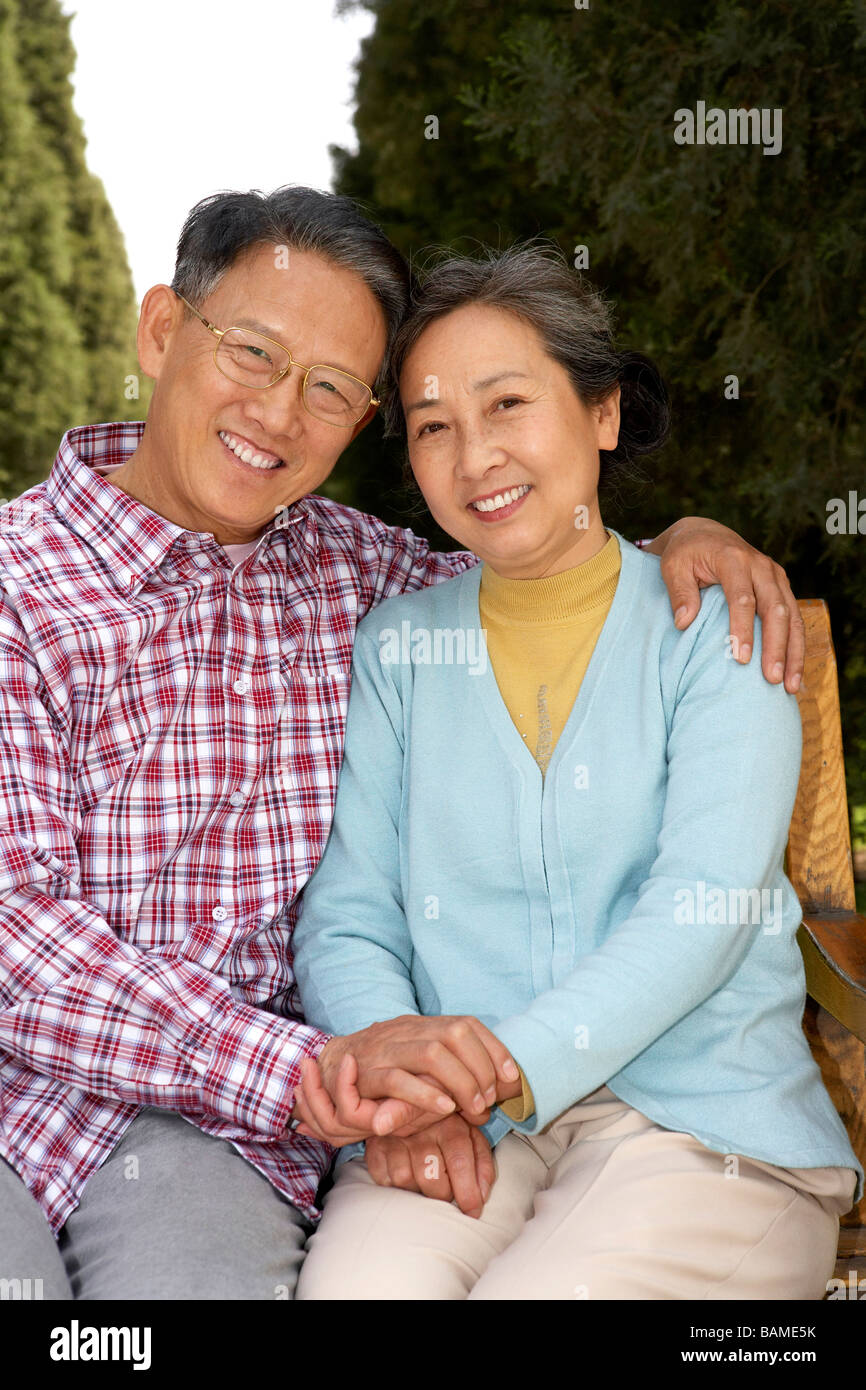 Senior Couple Sitting On Park Bench, Holding Hands Stock Photo - Alamy