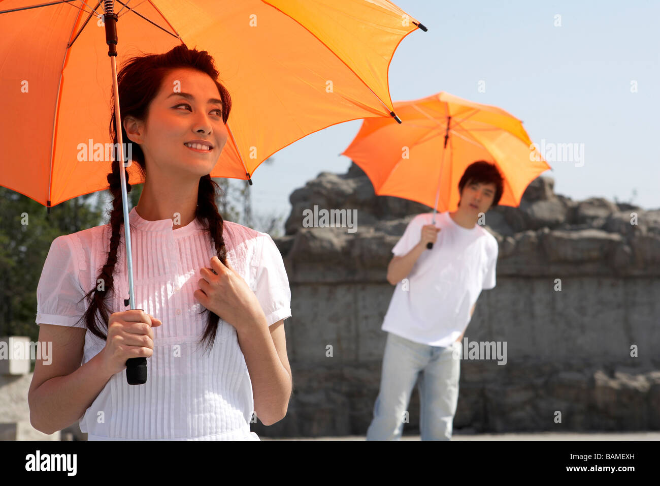 Young Man And Woman Holding Umbrellas Stock Photo - Alamy