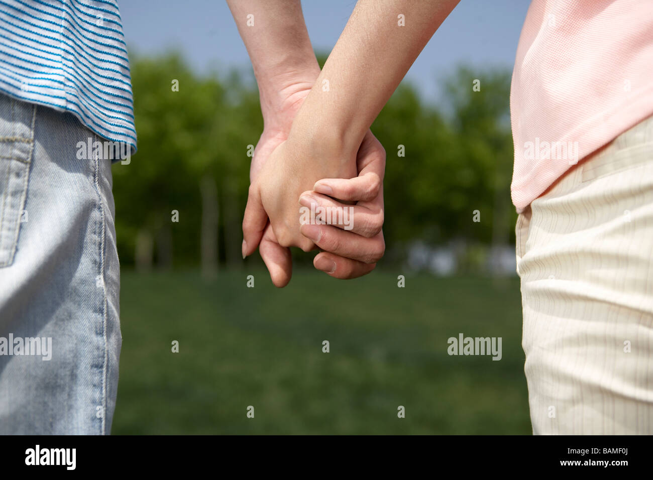 Couple Holding Hands In The Park Stock Photo - Alamy