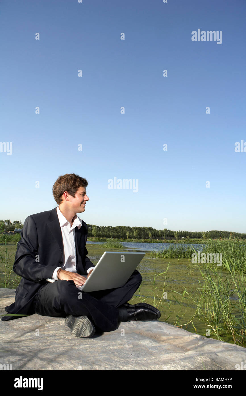 Businessman Sitting In A Field Using A Laptop Computer Stock Photo - Alamy
