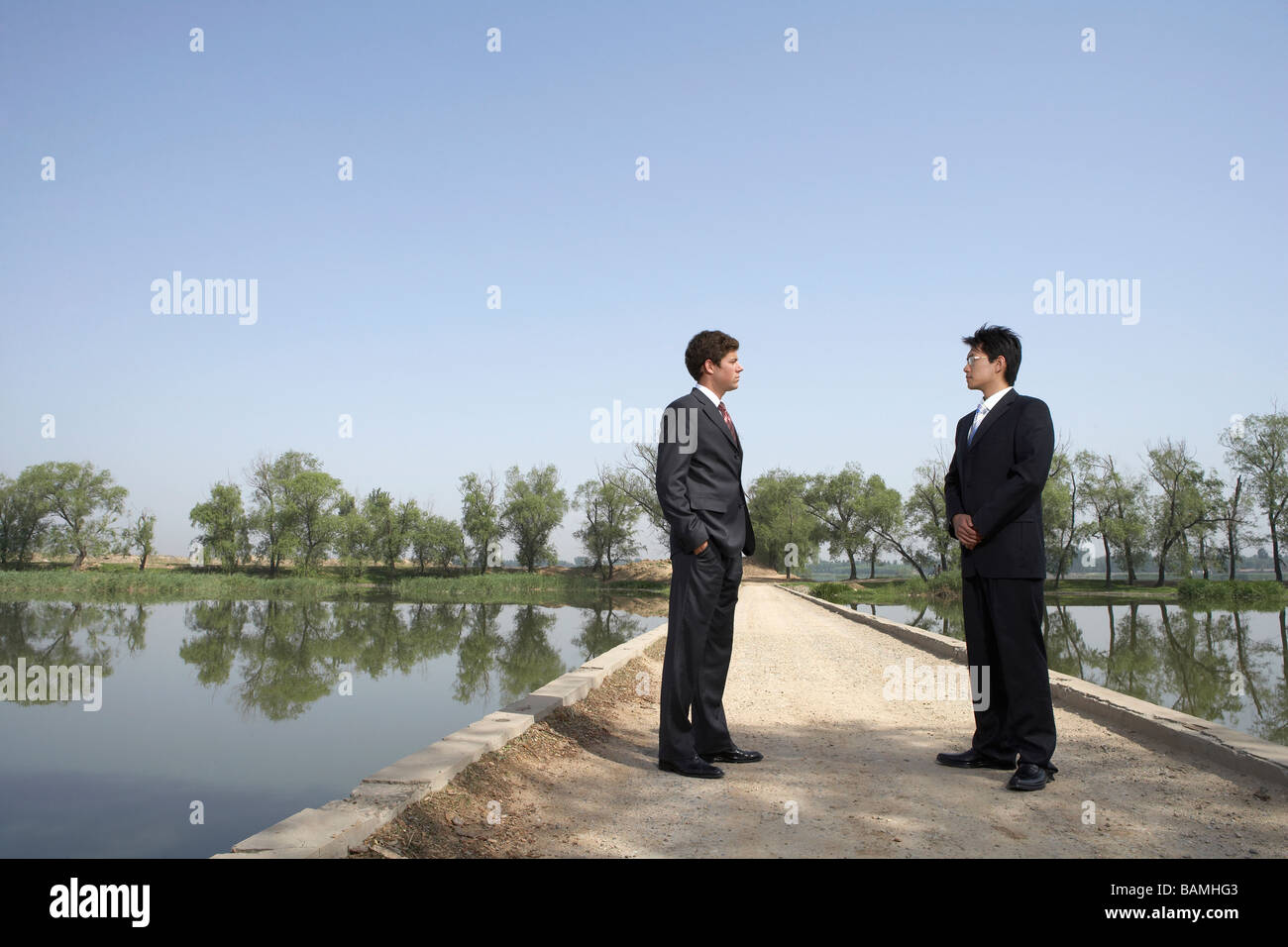 Businessmen Standing Next To A Lake On A Bridge Stock Photo