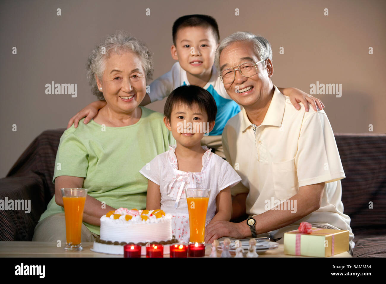 Grandparents And The Grandchildren Smile For The Camera On A Birthday Stock Photo