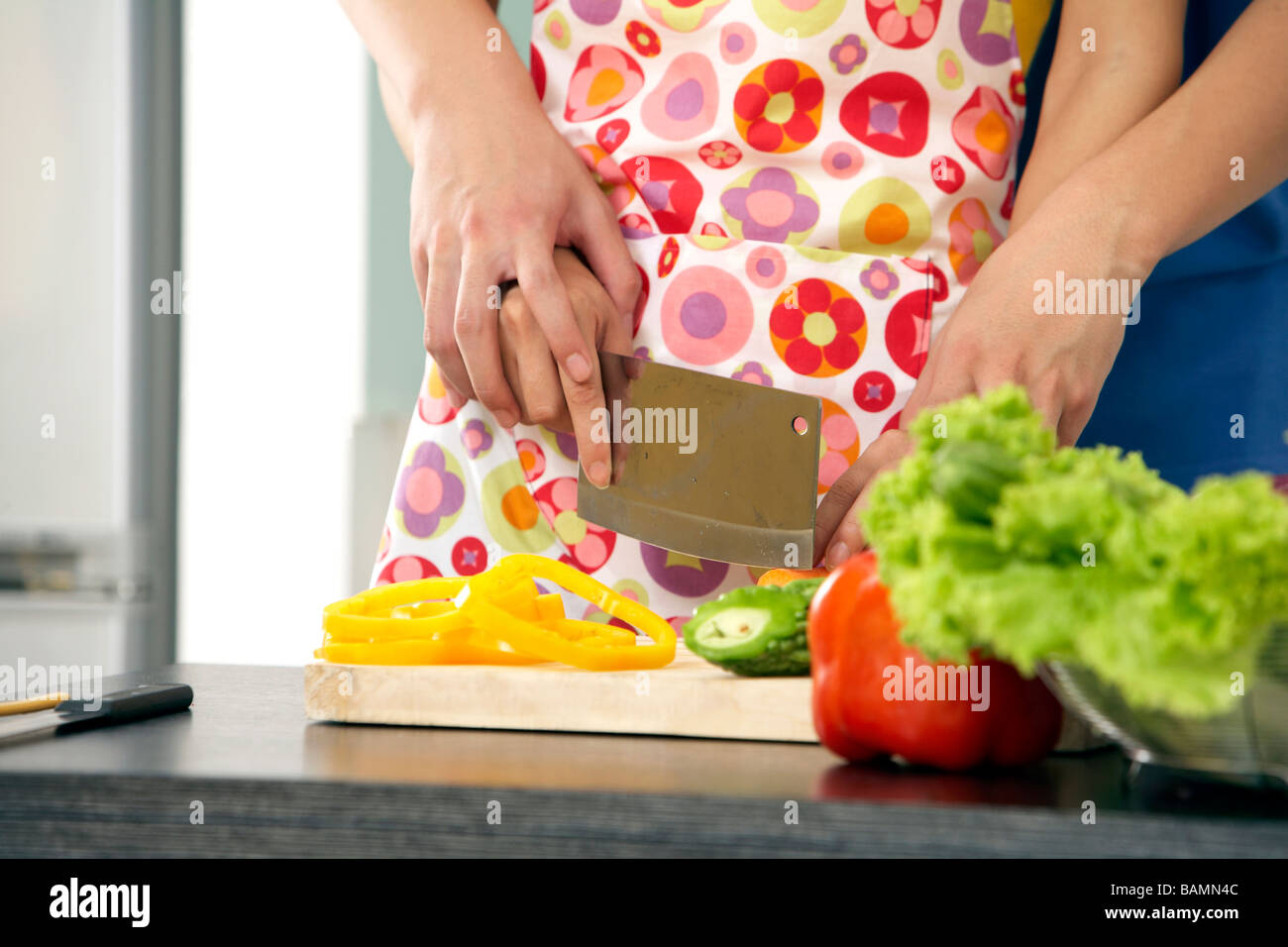 Young Couple Cutting Vegetables In The Kitchen Stock Photo