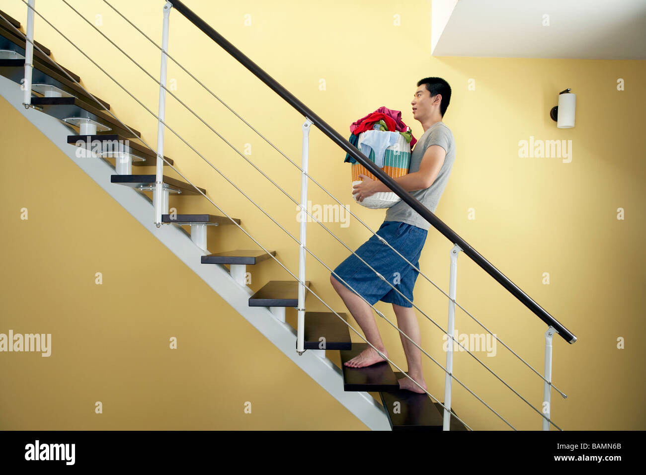 Portrait Of Man With A Clothes Basket On A Staircase Stock Photo